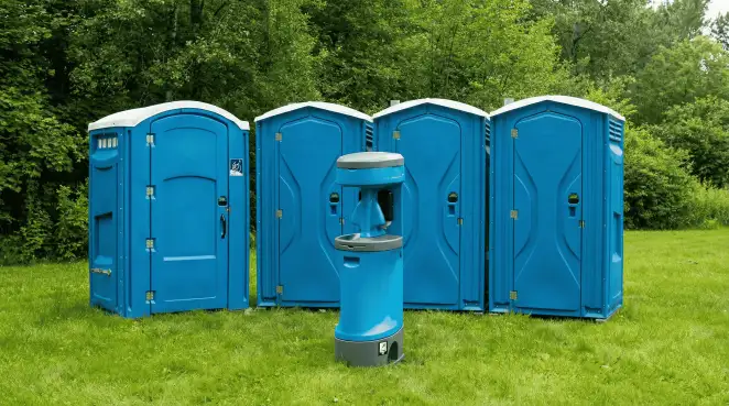 Four blue portable toilets and a matching hand washing station on grass near trees, a common sight at local outdoor events in Cape Coral, FL