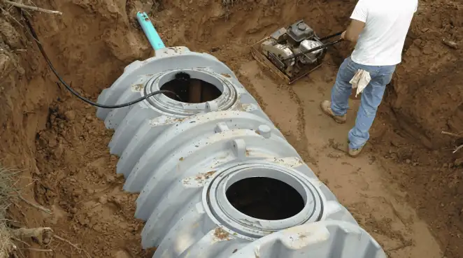 Septic tank installation showing a technician compacting soil around a new poly septic tank in an excavation pit in Cape Coral, FL
